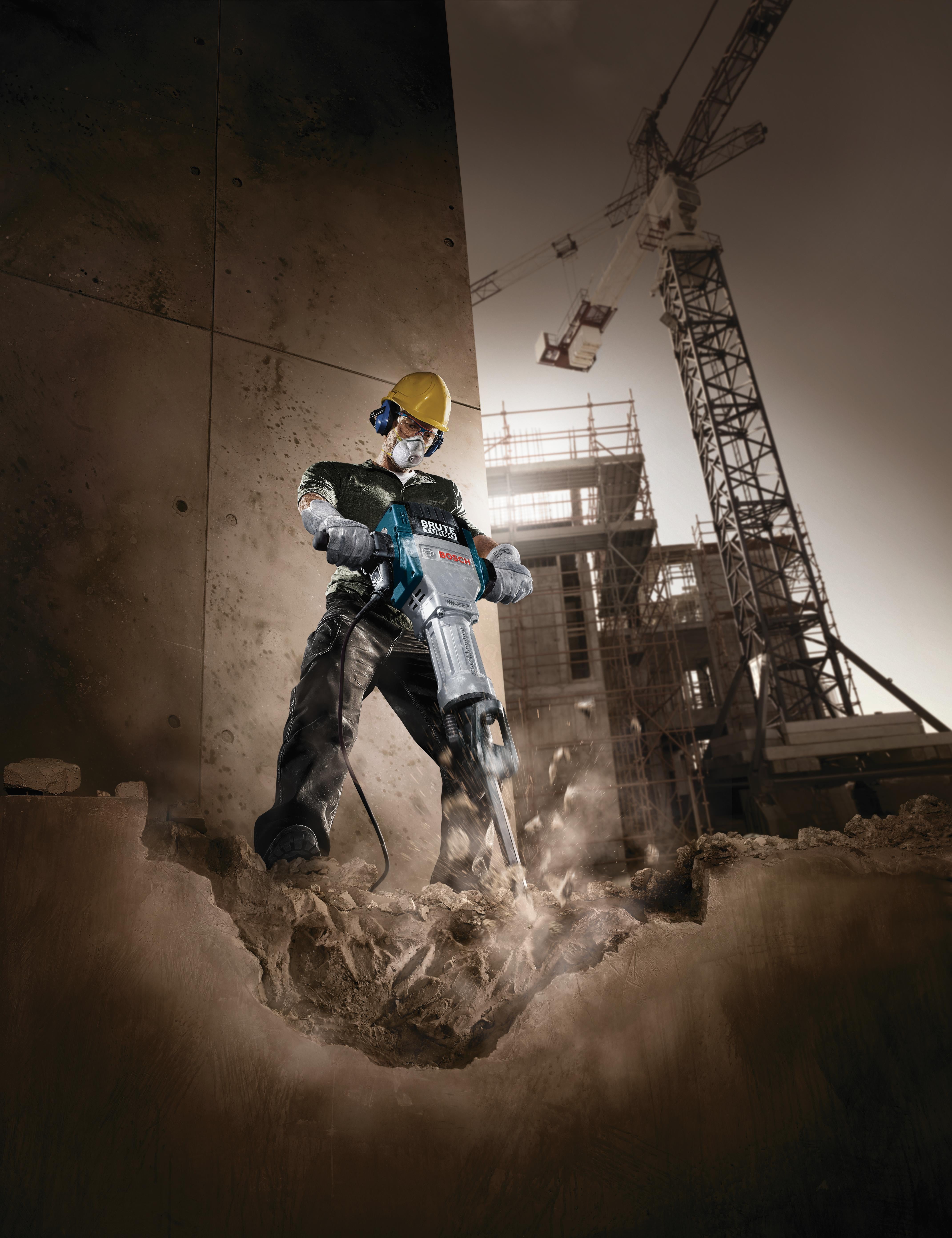 Worker breaking concrete on a site at dusk with the Bosch Brute Turbo breaker hammer