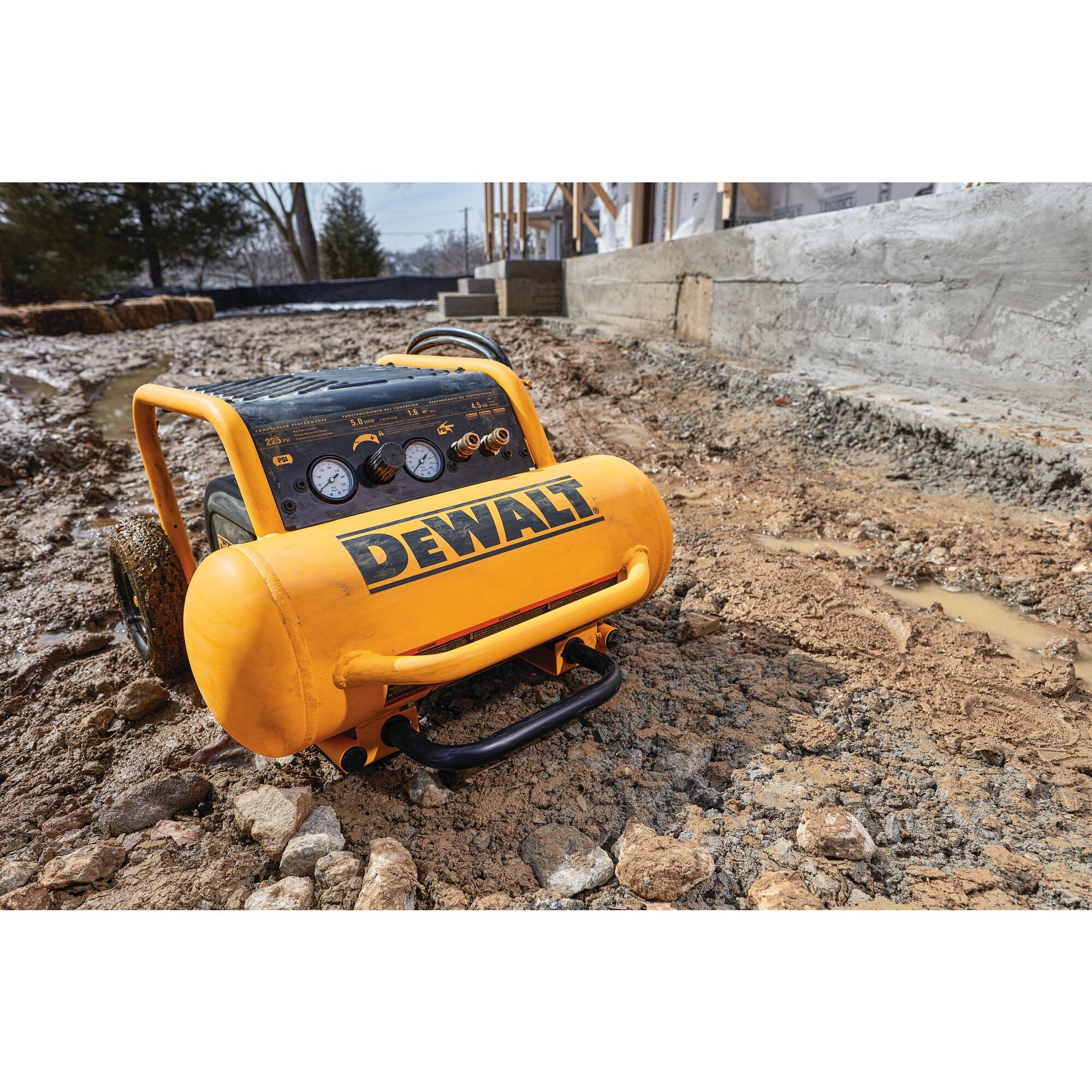 DeWalt 4.5 gallon compressor on rough ground beside a concrete foundation