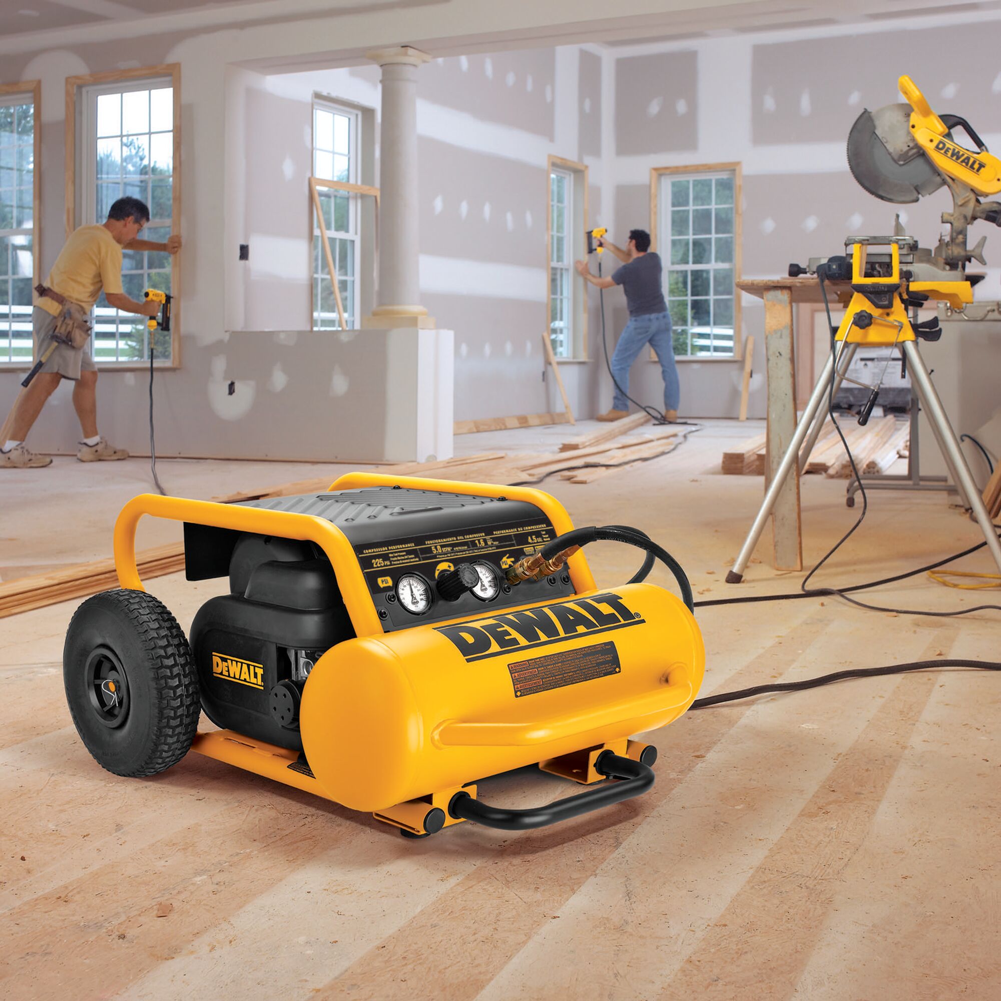 DeWalt 4.5 gallon compressor on a wooden floor in a house under construction, beside a mitre saw