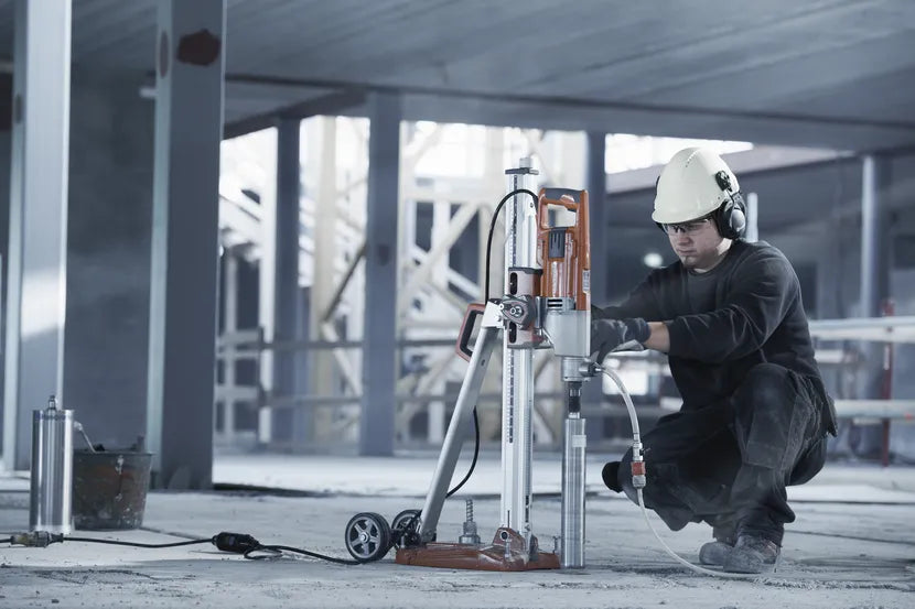 Operator coring a floor slab with a Husqvarna drill mounted on its stand