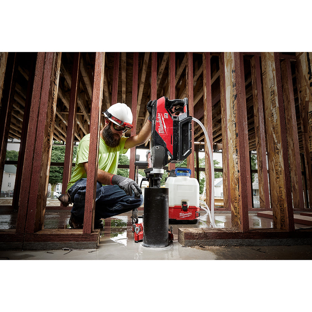 Operator coring a floor inside a timber-framed building with the compact core drill stand