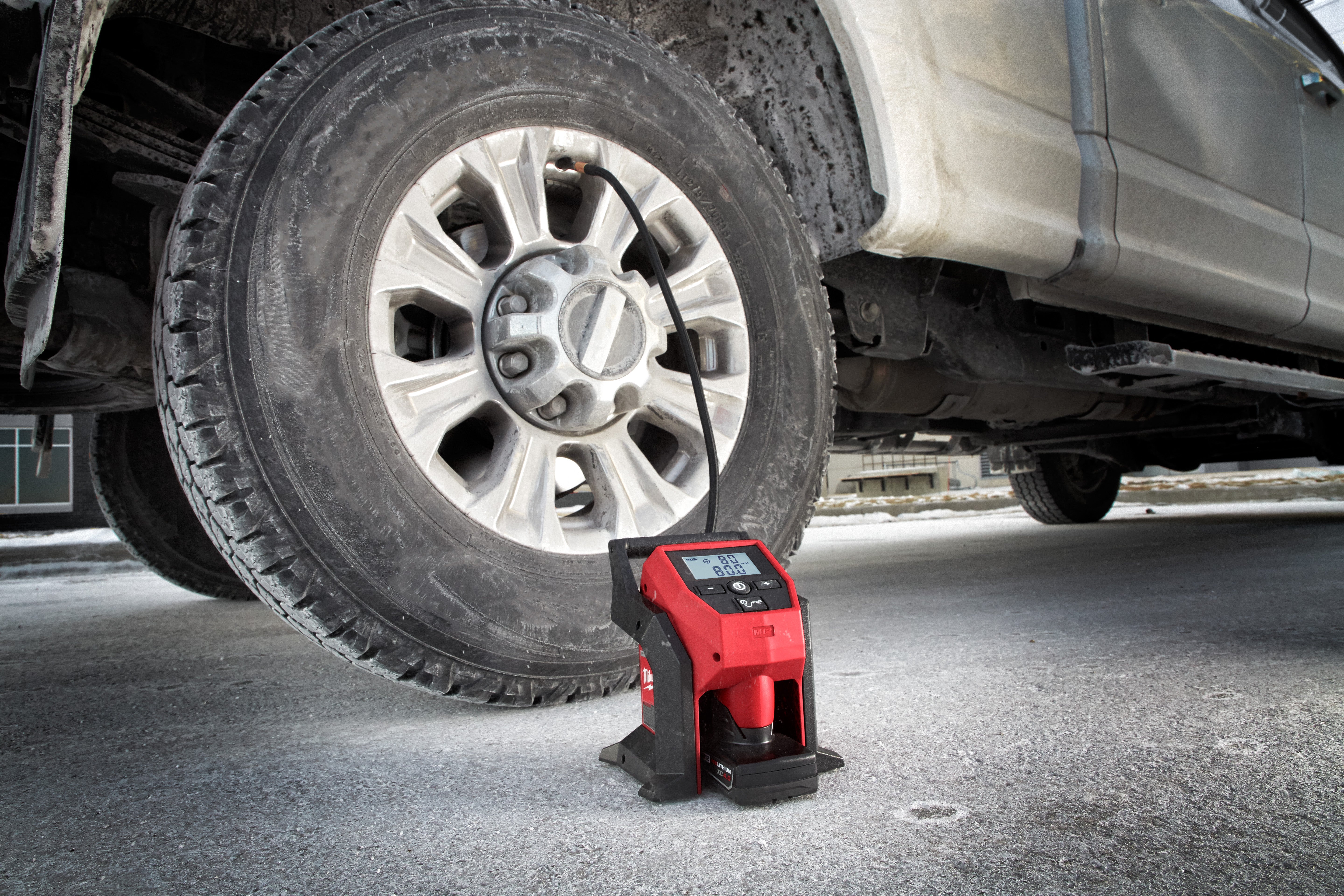 Milwaukee M12 compact inflator filling the tire of a pickup truck