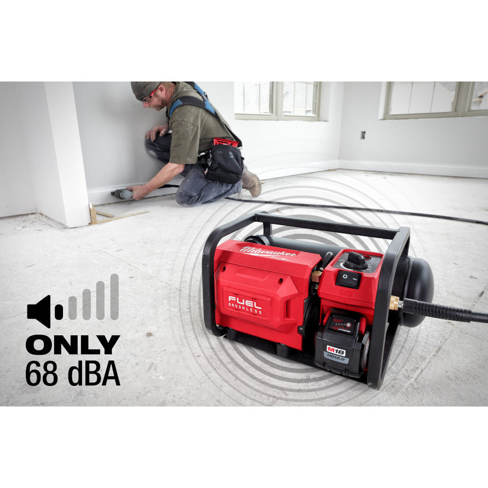Only 68 dBA: the M18 FUEL compressor running indoors while a worker nails flooring nearby