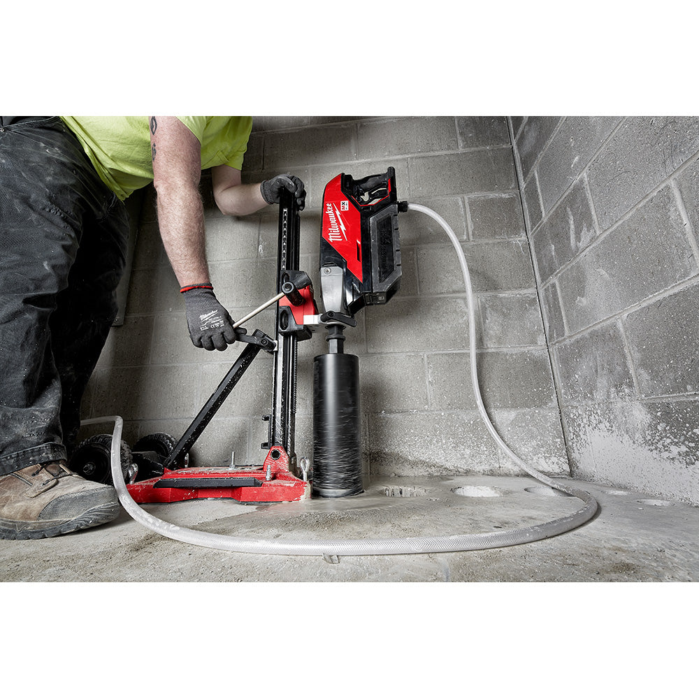 Operator coring a floor against a block wall with the core drill and compact stand